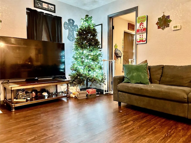 living area with dark wood-style flooring and a textured wall