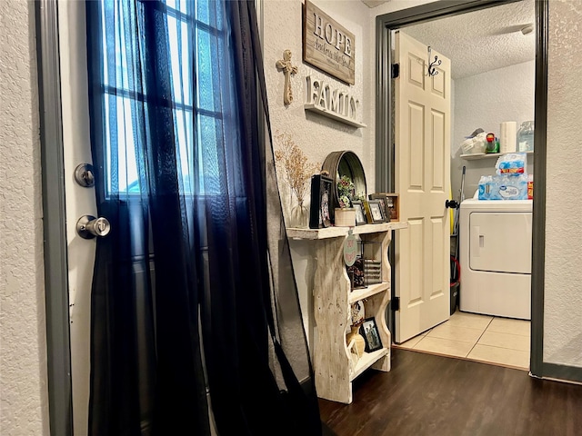 washroom with a textured wall, a textured ceiling, wood finished floors, washer / dryer, and laundry area