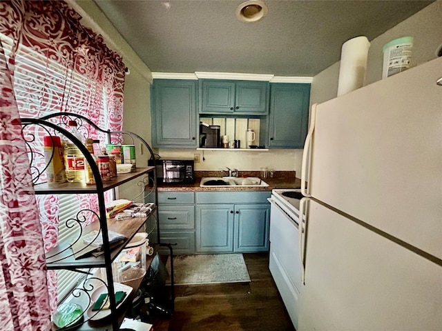 kitchen with dark countertops, white appliances, dark wood finished floors, and a sink