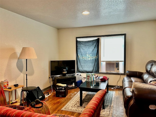 living area featuring a textured ceiling, wood finished floors, cooling unit, and baseboards