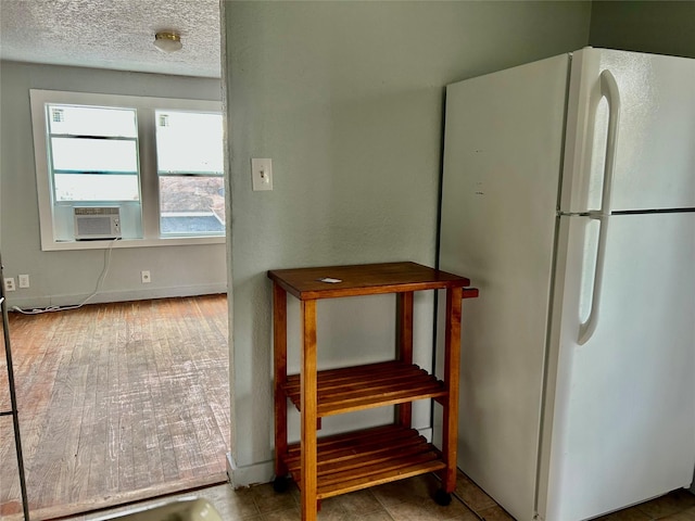 kitchen with a textured ceiling, cooling unit, and freestanding refrigerator