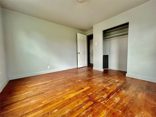 unfurnished bedroom with hardwood / wood-style flooring, baseboards, and a closet