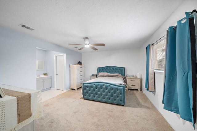 carpeted bedroom featuring ceiling fan, ensuite bath, and a textured ceiling