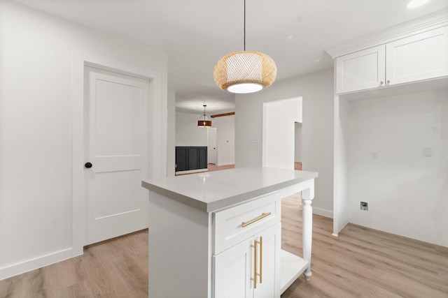 kitchen featuring white cabinets, hanging light fixtures, light hardwood / wood-style floors, and a center island