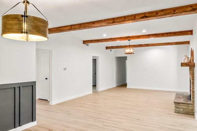 unfurnished room featuring a fireplace, light wood-type flooring, and beamed ceiling