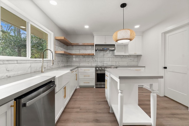 kitchen featuring white cabinetry, stainless steel appliances, pendant lighting, light hardwood / wood-style flooring, and backsplash