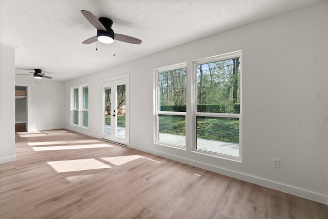 spare room featuring french doors, light wood-type flooring, a healthy amount of sunlight, and ceiling fan