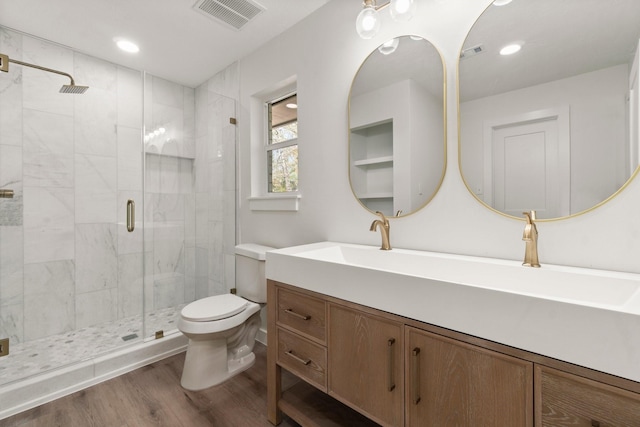 bathroom featuring toilet, wood-type flooring, vanity, and walk in shower