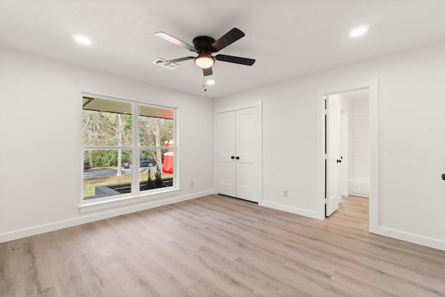 unfurnished bedroom with light wood-type flooring, ceiling fan, and a closet