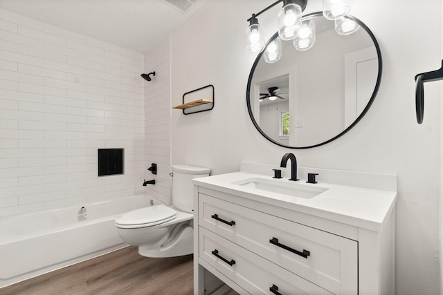 full bathroom featuring toilet, tiled shower / bath combo, ceiling fan, wood-type flooring, and vanity