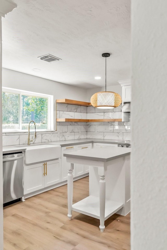 kitchen with dishwasher, pendant lighting, sink, white cabinetry, and backsplash