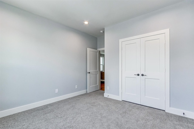 unfurnished bedroom featuring light carpet and a closet