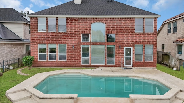 back of property featuring a lawn and a fenced in pool