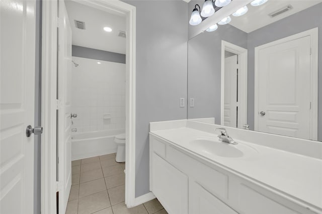 full bathroom with tile patterned floors, vanity, tiled shower / bath combo, and toilet