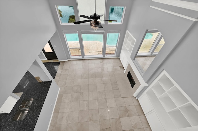 unfurnished living room featuring ceiling fan, light tile patterned floors, and a high ceiling