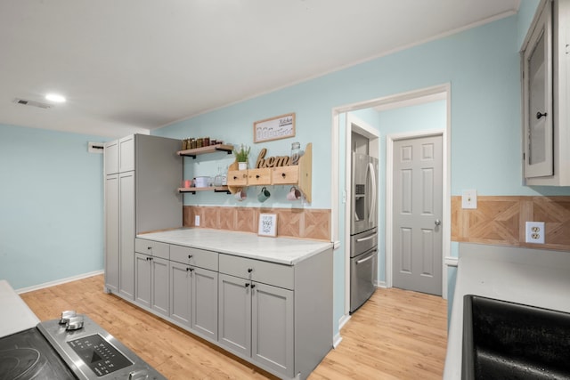 kitchen featuring gray cabinets, decorative backsplash, light hardwood / wood-style floors, and stainless steel refrigerator with ice dispenser