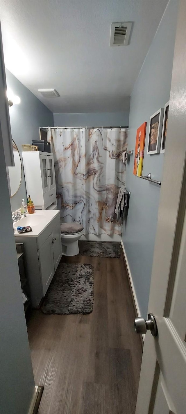 bathroom featuring wood-type flooring, vanity, toilet, and walk in shower