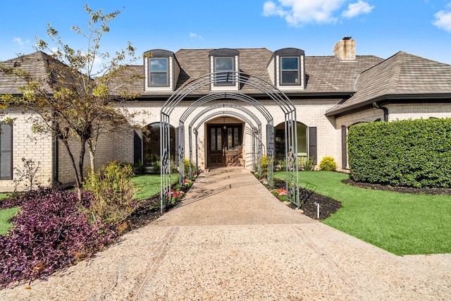 french provincial home with a front yard and french doors