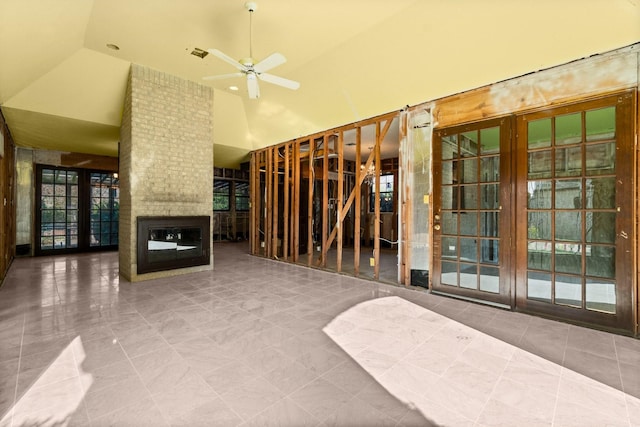 interior space with ceiling fan, a fireplace, and high vaulted ceiling