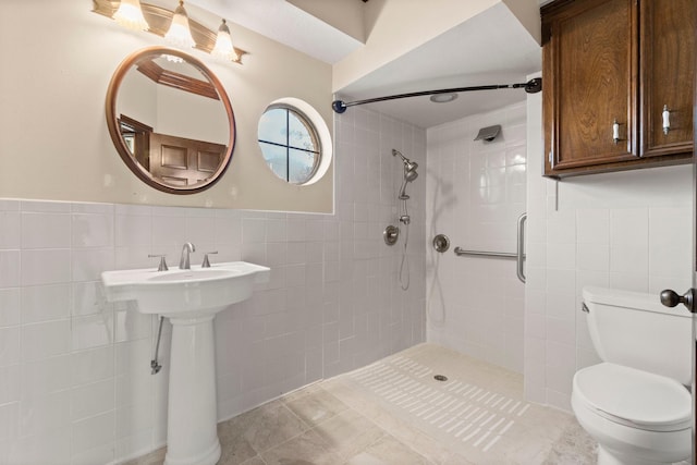 bathroom with tiled shower, tile patterned floors, toilet, and tile walls