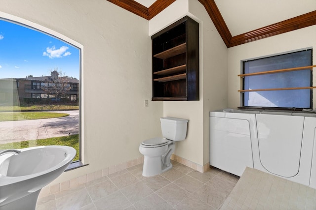 bathroom with lofted ceiling, crown molding, tile patterned flooring, toilet, and separate washer and dryer