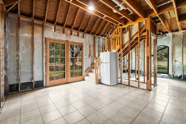 basement with light tile patterned floors and white refrigerator