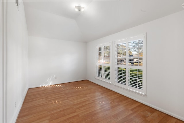 empty room with light wood-type flooring and vaulted ceiling