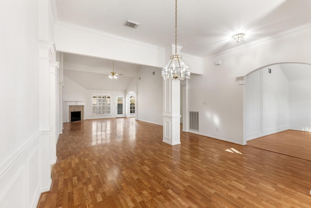 unfurnished living room with ornate columns, wood-type flooring, lofted ceiling, a fireplace, and ceiling fan with notable chandelier