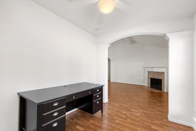 office space with lofted ceiling with beams, hardwood / wood-style flooring, ceiling fan, and a tiled fireplace