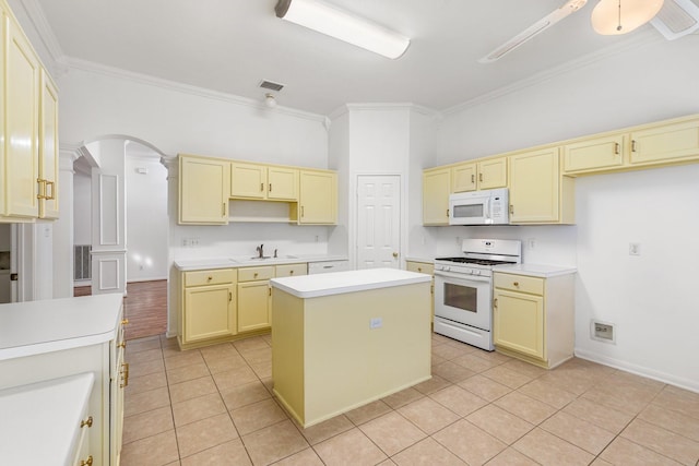 kitchen featuring white appliances, a kitchen island, ornamental molding, and sink