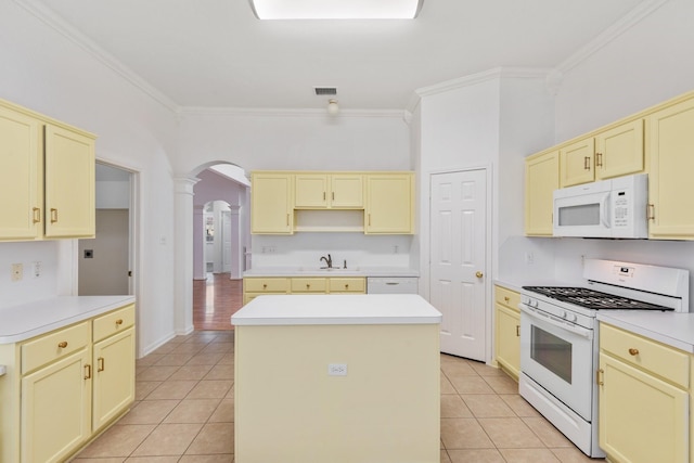 kitchen featuring sink, a center island, white appliances, light tile patterned floors, and ornamental molding