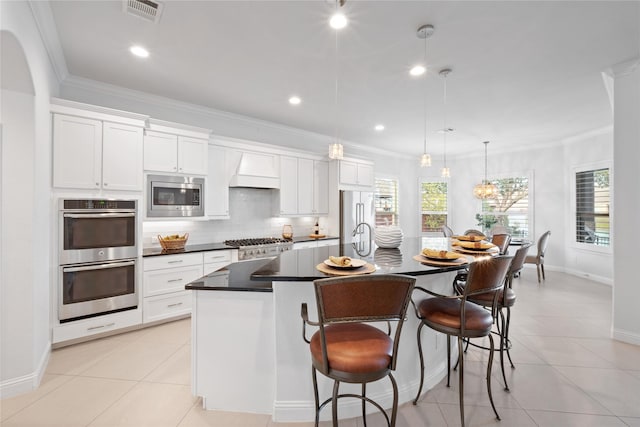 kitchen with white cabinetry, an island with sink, hanging light fixtures, and appliances with stainless steel finishes