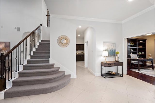 stairway with tile patterned floors, built in shelves, and ornamental molding