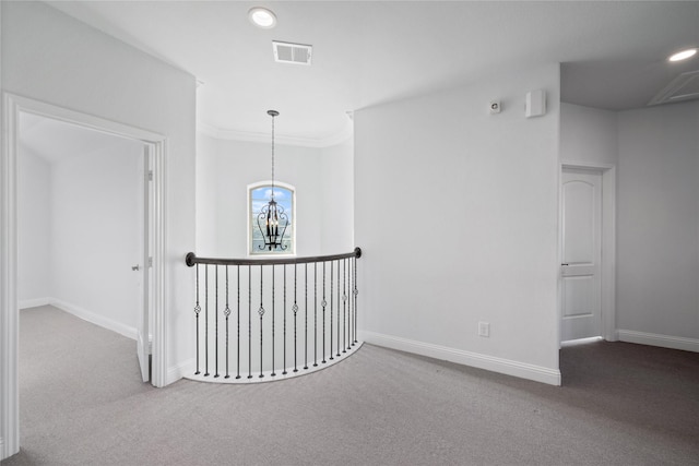 corridor featuring carpet floors, crown molding, and a chandelier