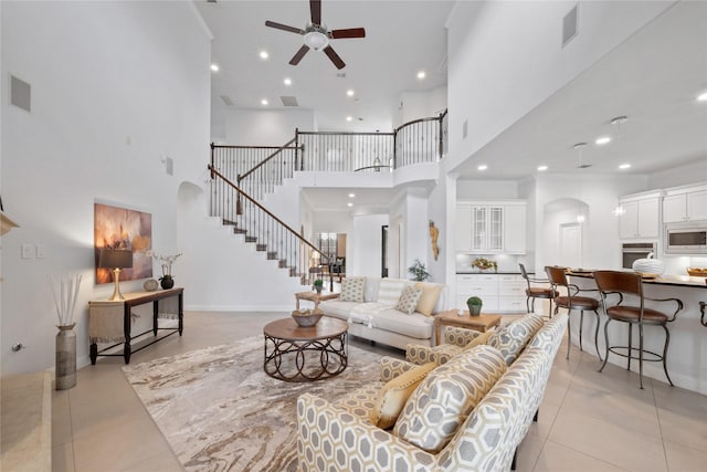 tiled living room featuring ceiling fan, a towering ceiling, and crown molding