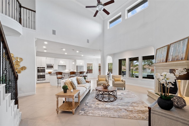 living room with ceiling fan, light tile patterned floors, and a high ceiling