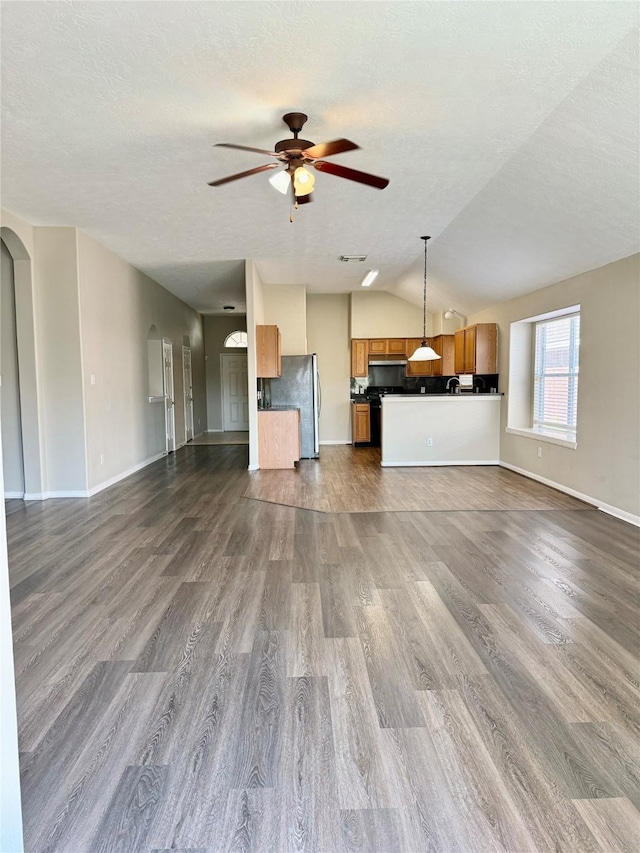 unfurnished living room featuring a textured ceiling, ceiling fan, dark hardwood / wood-style flooring, and lofted ceiling