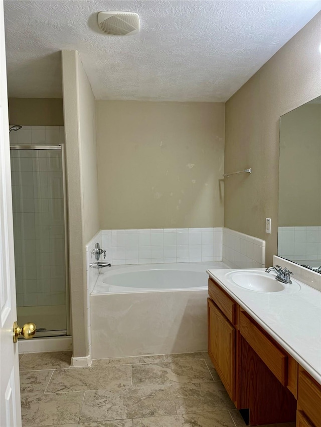 bathroom with vanity, shower with separate bathtub, and a textured ceiling