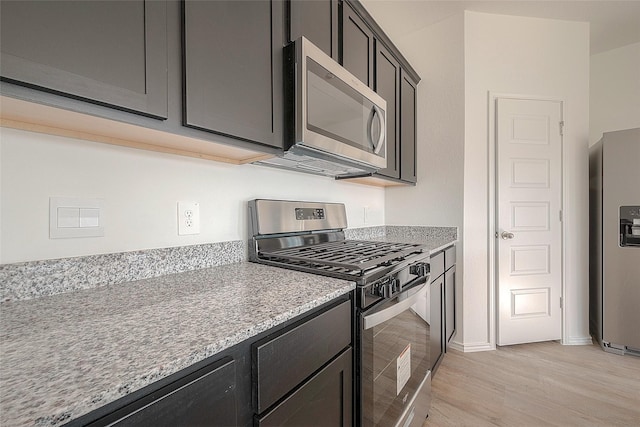 kitchen featuring appliances with stainless steel finishes, light hardwood / wood-style floors, and light stone counters