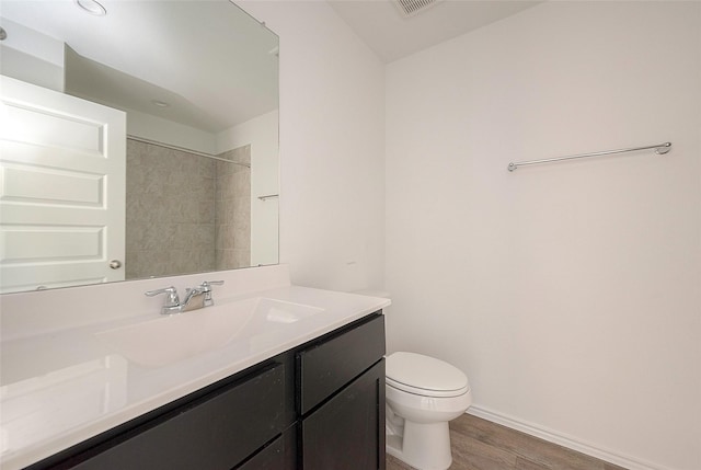 bathroom featuring vanity, toilet, wood-type flooring, and a tile shower