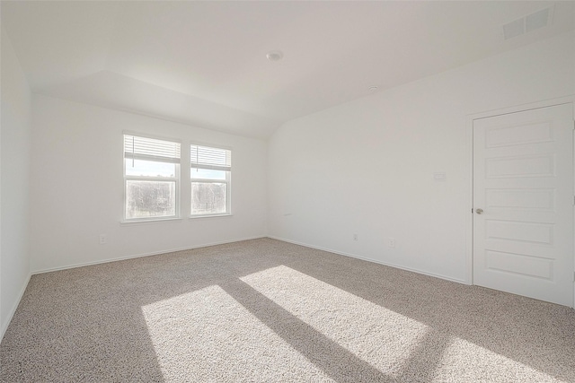 carpeted empty room with vaulted ceiling