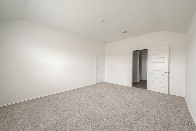 spare room with dark colored carpet and lofted ceiling