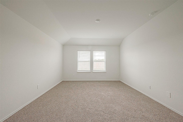 carpeted empty room with vaulted ceiling