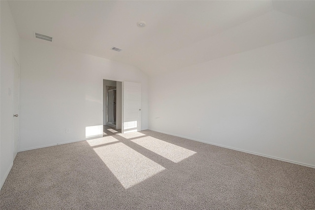 carpeted spare room featuring vaulted ceiling