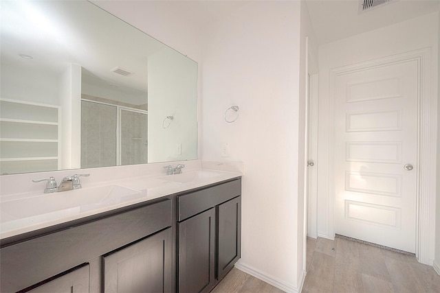 bathroom with hardwood / wood-style floors, vanity, and a shower with door