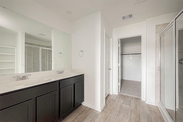 bathroom with wood-type flooring, vanity, and walk in shower