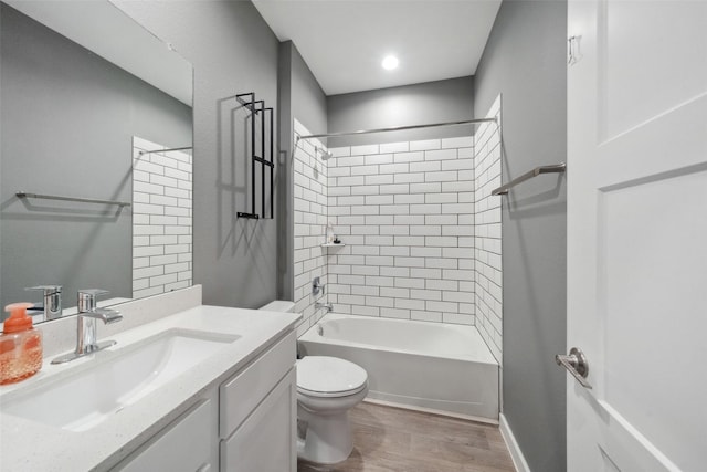 full bathroom featuring hardwood / wood-style flooring, vanity, tiled shower / bath combo, and toilet