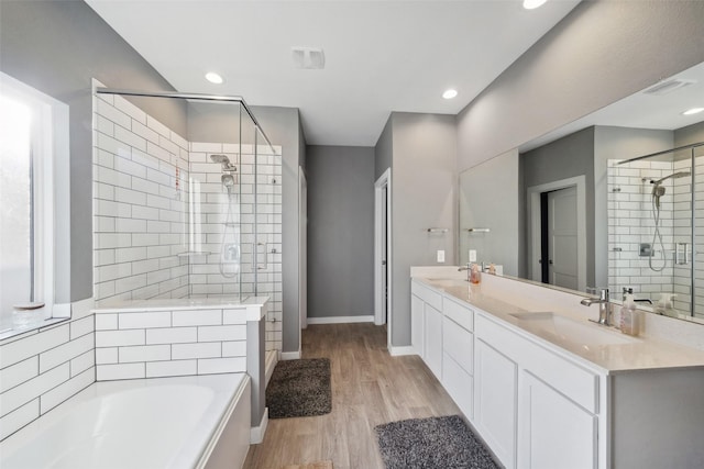 bathroom with hardwood / wood-style flooring, vanity, and plus walk in shower