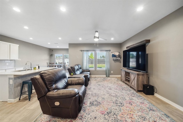 living room with ceiling fan, sink, and light hardwood / wood-style flooring