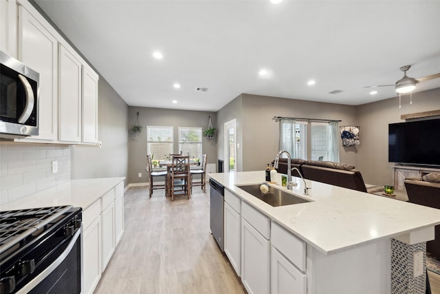 kitchen with tasteful backsplash, stainless steel appliances, sink, a center island with sink, and white cabinets